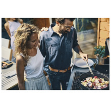 Ein Paar bereitet Mahlzeiten auf einem Gasgrill im Freien zu.