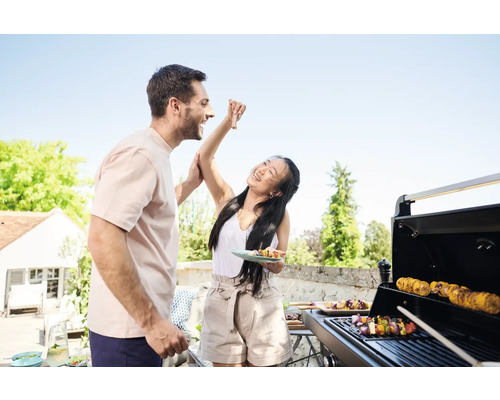Mann und Frau grillen im Freien und essen Fleischspieße.