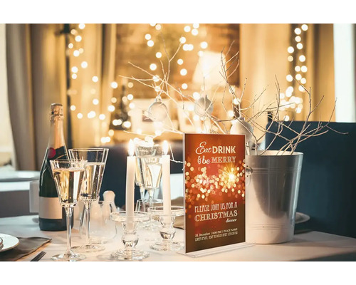 Festlich gedeckter Tisch mit Champagner, Gläsern, Kerzen und einer Einladungskarte für ein Weihnachtsdinner