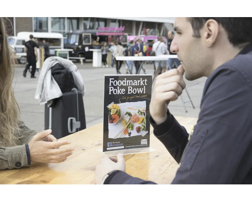 Aufsteller mit Werbung für Foodmarkt Poke Bowl auf einem Tisch