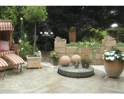 Gestalteter Gartenbereich mit Strandkorb, Mauer und Pflanzgefäßen.