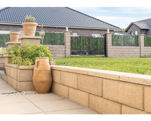 Gartenansicht mit Pflanzkübeln, Mauer aus Betonsteinen und Zaun mit Sichtschutz