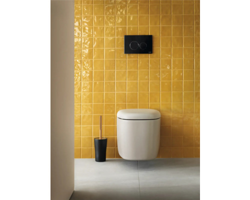 Wand-WC mit Spülkasten und Toilettenbürste vor gelber Fliesenwand