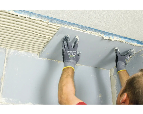 Fliesenleger bei der Anbringung einer Fliese an der Wand