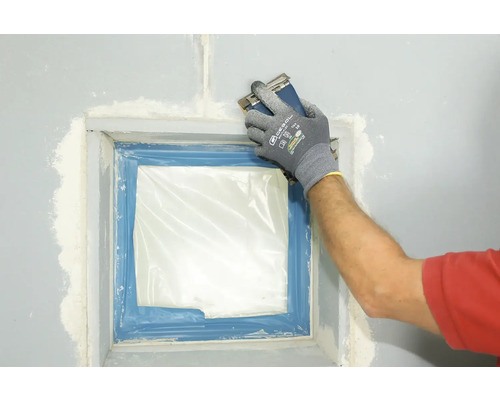 Hand mit Schleifklotz schleift Wand nach dem Verputzen eines Fensters