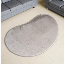 Bohnenförmiger Teppich auf Fliesenboden zwischen zwei Sofas