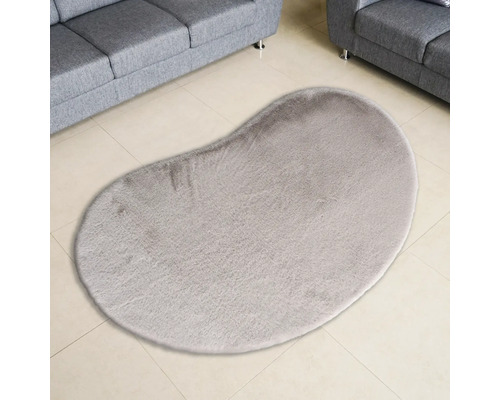 Bohnenförmiger Teppich auf Fliesenboden zwischen zwei Sofas