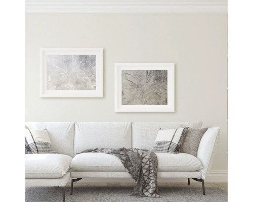 Wohnzimmer mit Sofa, Kissen, Decke und zwei gerahmten Kunstdrucken