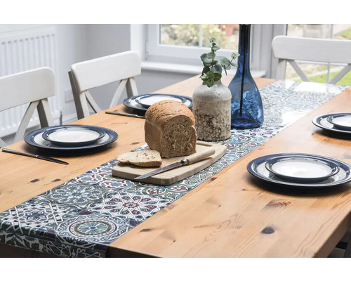 Esstisch mit Tischläufer, Geschirr, Brot und Dekoration