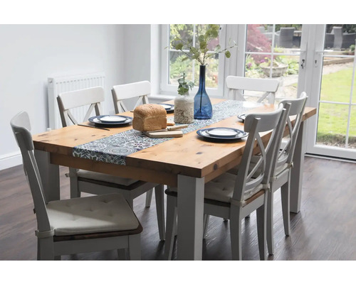 Esstisch mit Stühlen, Tischdeko, Geschirr und Brot in einem hellen Esszimmer.