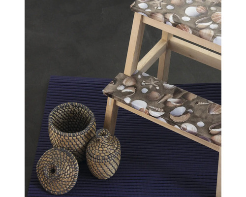 Szene mit Holztrittschemel mit Muschelmuster, zwei Körben und einem Teppich