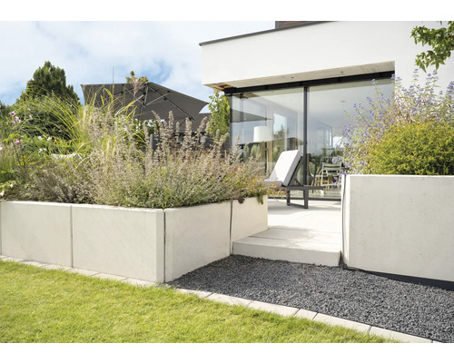 Modern gestalteter Garten mit Rasenfläche, Hochbeet aus Betonsteinen und Terrasse mit Gartenmöbeln