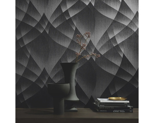 Innenaufnahme eines Raumes mit einer gemusterten Tapete, Büchern und Vasen auf einem Tisch.