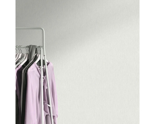 Helle Wandtapete mit Textilmuster neben einer Kleiderstange