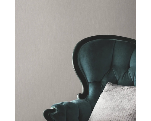 Nahaufnahme einer strukturierten Tapete mit einem Sessel im Hintergrund.