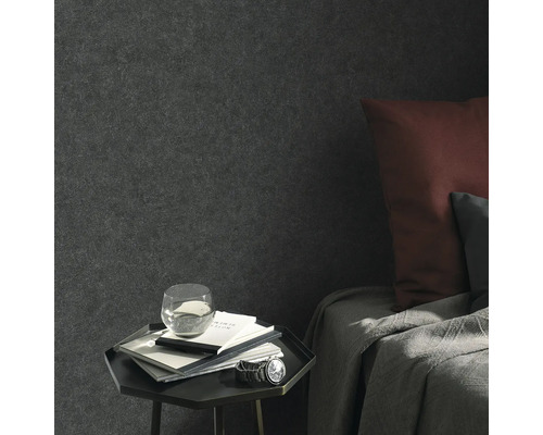 Wohnraumszene mit Textiltapete, Nachttisch, Notizbüchern, Glas Wasser und Armbanduhr