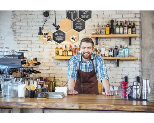 Gastronomieszene mit Barkeeper hinter der Theke und hexagonförmigen Wanddekorationen