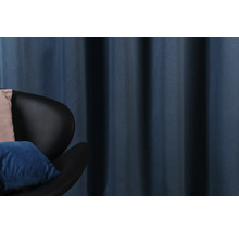 Dekorativer blauer Vorhang neben einem schwarzen Sessel mit Kissen