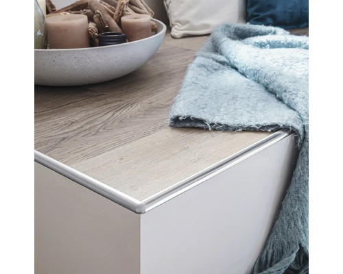 Abschlussleiste aus Aluminium an einer weißen Kommode mit Holzboden