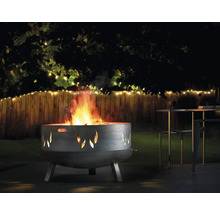 Feuerstelle mit Flammenmuster in einem Garten mit Zaun und Tisch