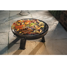 Runder Grill mit Grillgut wie Fleisch, Gemüse und Spießen auf einem Steinboden
