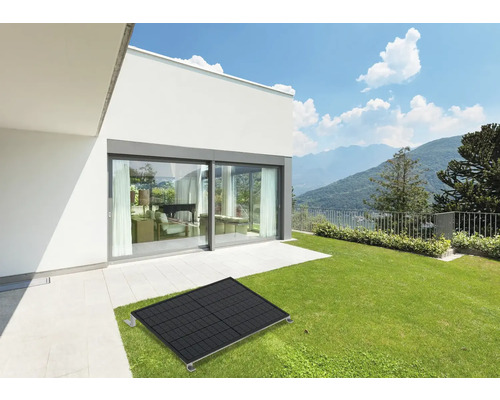 Solarpanel auf Rasen vor modernem Haus mit Schiebetür