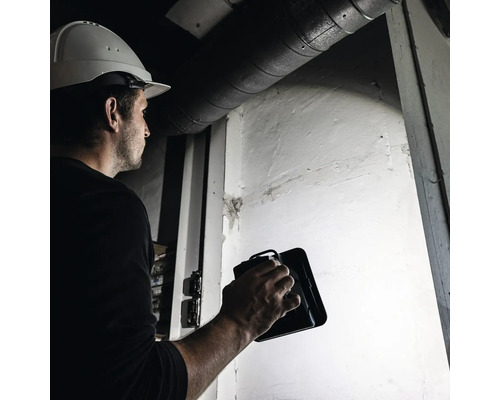 Handwerker mit LED-Arbeitsleuchte bei der Arbeit in Innenräumen