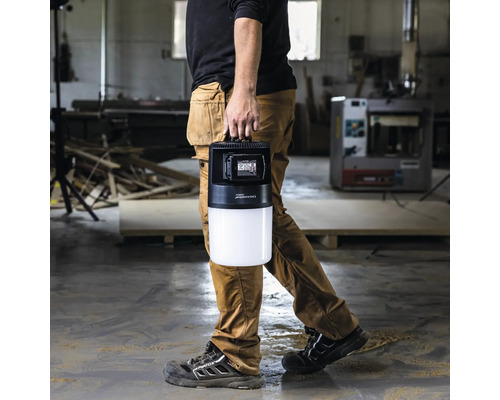 Eine Person trägt eine tragbare LED-Baustellenleuchte