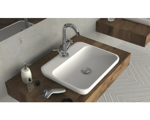 Waschtisch mit Armatur, Seifenspender und Rasierer auf Holzablage im Badezimmer