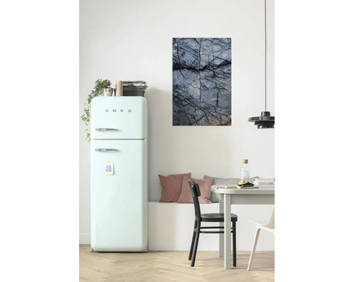 Wohnraum mit Kühlschrank, Esstisch und einem Wandbild mit Steinmotiv.