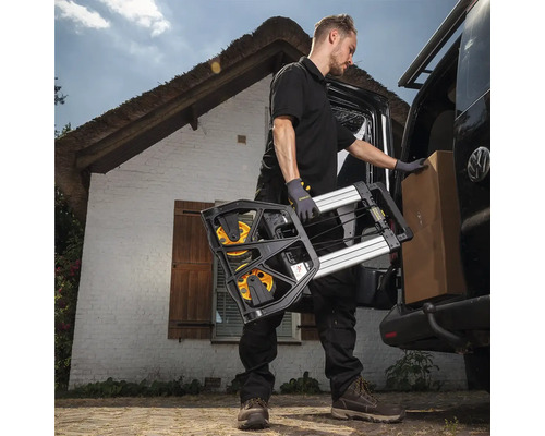 Mann lädt Sackkarre und Karton aus einem Lieferwagen vor einem Haus