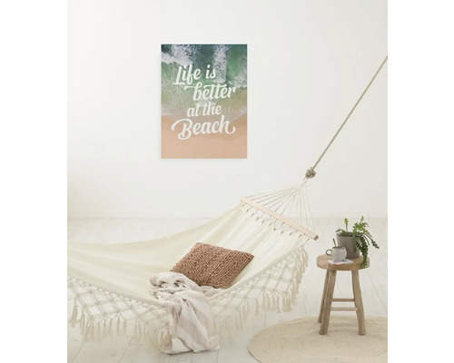 Szene mit Hängematte, Beistelltisch und Wandbild mit dem Schriftzug: Life is better at the Beach