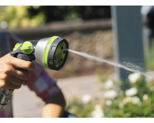 Hand hält eine Gartenspritze, aus der Wasser austritt.