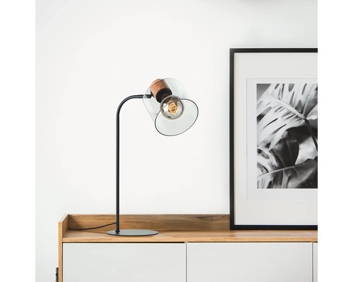 Tischleuchte mit Glasschirm und Glühbirne auf einem Sideboard