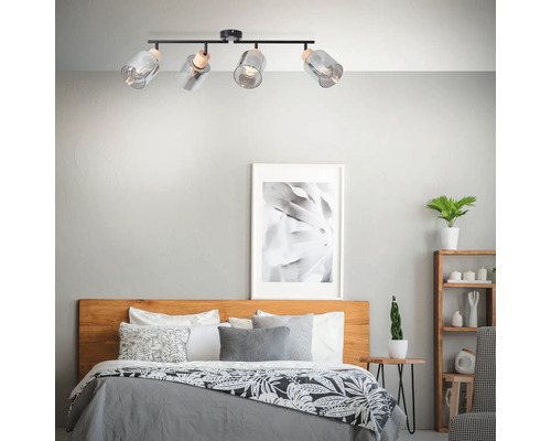 Deckenleuchte mit vier Glaslampenschirmen über einem Bett in einem Schlafzimmer.