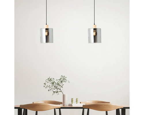 Zwei Pendelleuchten aus Glas und Holz über einem Esstisch.