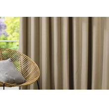 Dekorativer Vorhang neben einem Rattansessel vor einem Fenster