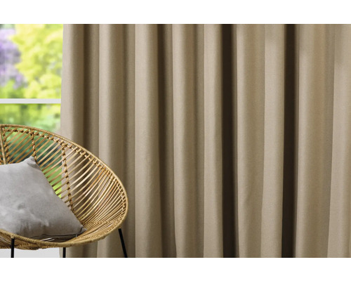 Dekorativer Vorhang neben einem Rattansessel vor einem Fenster