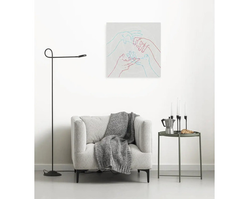 Wohnzimmer mit Sessel, Stehlampe und Wandbild mit Händen