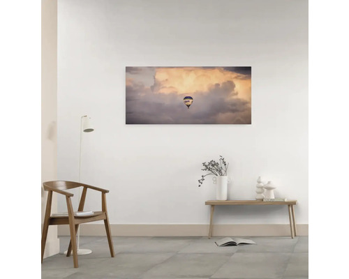 Wandbild mit einem Heißluftballon vor Wolken in einem Zimmer.