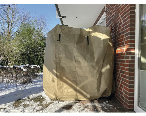 Abgedeckter Grill mit Schutzhülle auf einer Terrasse im Winter.