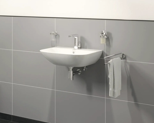 Waschbecken mit Armatur, Seifenspender, Zahnputzbecher und Handtuchhalter an grauer Wand