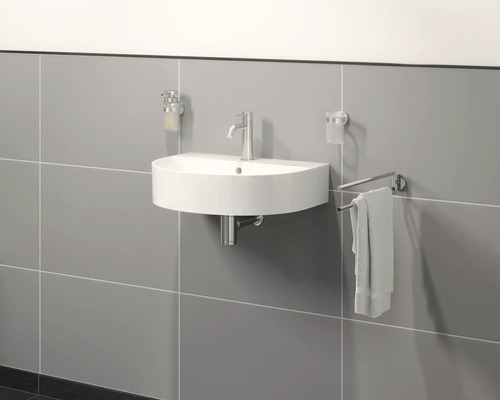 Wandmontiertes Waschbecken mit Armatur, Seifenspender, Becher und Handtuchhalter im Badezimmer