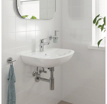 Badezimmerwaschbecken mit Armatur, Seifenspender und Handtuchhalter an einer gefliesten Wand