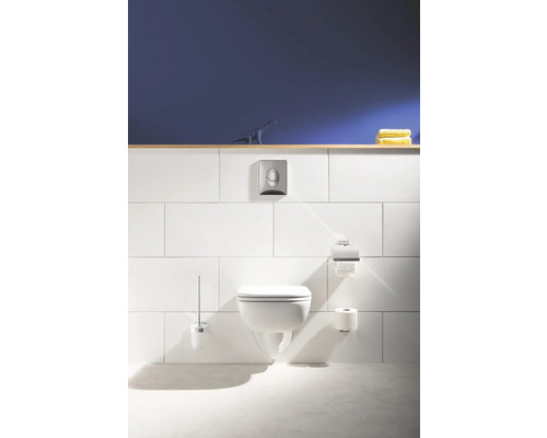 Hänge-WC mit Betätigungsplatte, Toilettenpapierhalter und Bürstengarnitur in einem hellen Badezimmer.