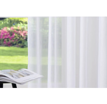 Weißer Gardinenschal vor einem Fenster mit Gartenblick