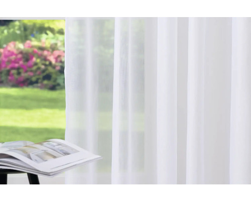 Weißer Gardinenschal vor einem Fenster mit Gartenblick