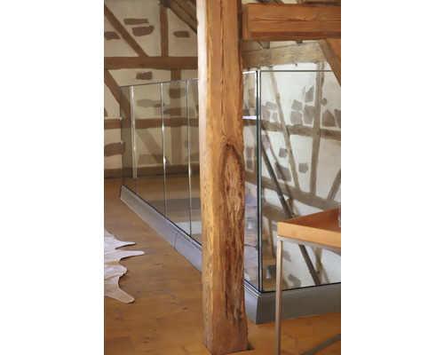 Innenraum mit Holzstütze und Glasgeländer.
