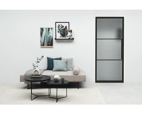 Helles Wohnzimmer mit Tagesbett, Couchtischen, Dekoration und Tür mit Glaseinsatz