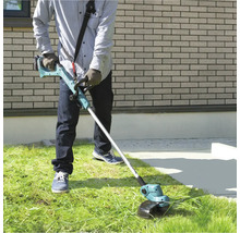 Mann bedient einen Akku-Rasentrimmer im Garten.